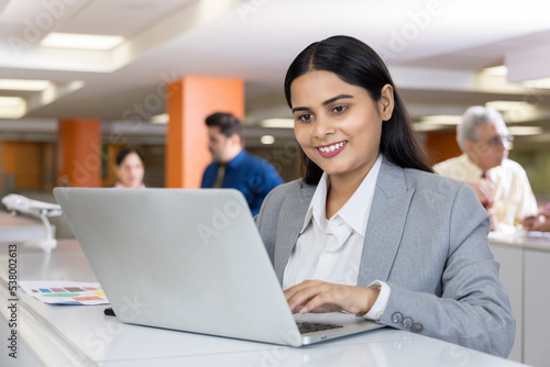 Happy indian businesswoman using laptop in office