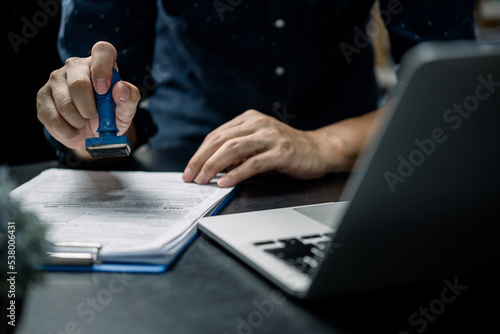 Fototapete Man stamping approval of work finance banking or investment marketing documents on desk