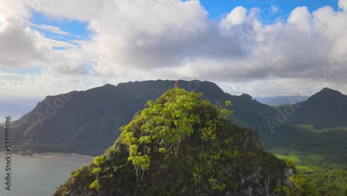 Drone aerial view of a man standing at the top of Pu’u Piei mountain peak at Kahana Valley State Park in Oahu Hawaii. photo