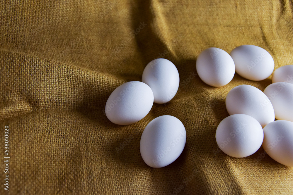 White chicken eggs close-up on a background of burlap, rustic still life. Concept and idea for homemade organic food artwork. environmentally friendly products. Farm products White chicken eggs close-up on a background of burlap, rustic still life. Concept and idea for homemade organic food artwork. environmentally friendly products. Farm products