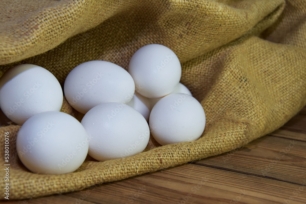 White chicken eggs close-up on a background of burlap, rustic still life. Concept and idea for homemade organic food artwork. environmentally friendly products. Farm products White chicken eggs close-up on a background of burlap, rustic still life. Concept and idea for homemade organic food artwork. environmentally friendly products. Farm products