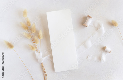 Blank card near silk ribbons and dried hare's tail grass top view on white, boho mockup