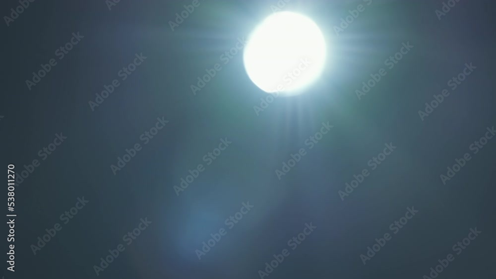 Real lens flare. Sun motion effect. Moving light circle and beams on dark background Real lens flare. Sun motion effect. Moving light circle and beams on dark background