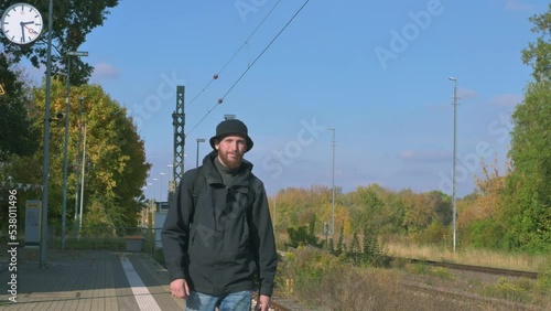 young man with a beard walks briskly along the platform of the railway station