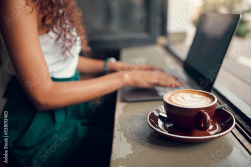 Laptop, coffee and woman remote work typing proposal, for planning business and in cafe. Entrepreneur, female student and lady working on startup company, strategy and with hot beverage or latte.
