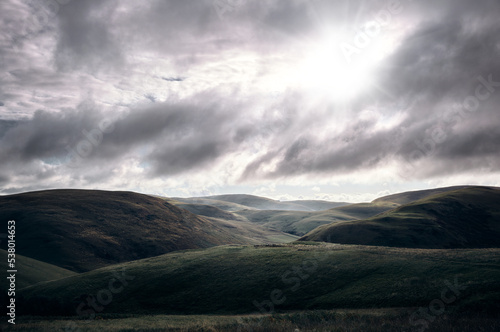Early morning sun breaking through the cloud over Coquetdale, the Cheviot Hills in Northumberland, England, UK.