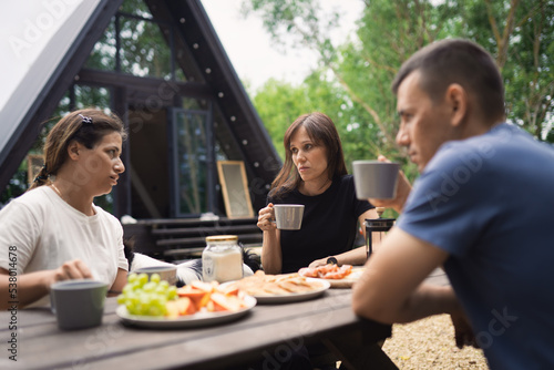 Group friends enjoying tea and talk at patio, celebrating weekend reunion gathering. selective focus