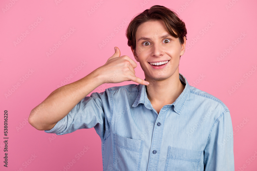 Photo of good ooking young man in shirt isolated on pastel background making gesture call me with his fingers Photo of good ooking young man in shirt isolated on pastel background making gesture call me with his fingers