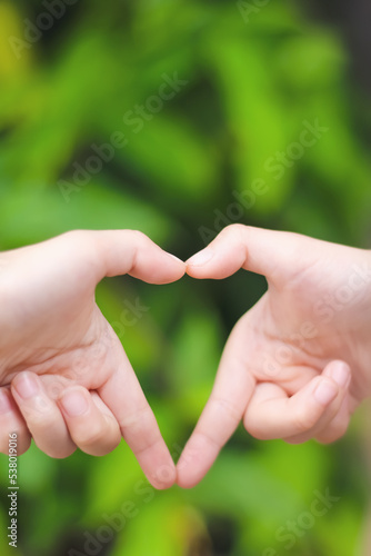 Asian child girl hands making heart shape on green garden background for Father , Mother's Day or Valentine day concept © Amphawan