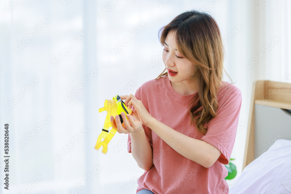 Millennial Asian young happy cheerful thoughtful female teenager sitting smiling on cozy bed in bedroom at home checking clothes preparing for weekend vacation Millennial Asian young happy cheerful thoughtful female teenager sitting smiling on cozy bed in bedroom at home checking clothes preparing for weekend vacation