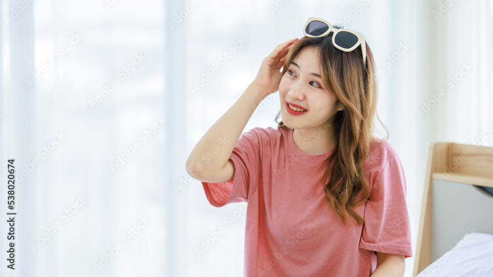 Millennial Asian young happy cheerful thoughtful female teenager sitting smiling on cozy bed in bedroom at home checking clothes preparing for weekend vacation Millennial Asian young happy cheerful thoughtful female teenager sitting smiling on cozy bed in bedroom at home checking clothes preparing for weekend vacation