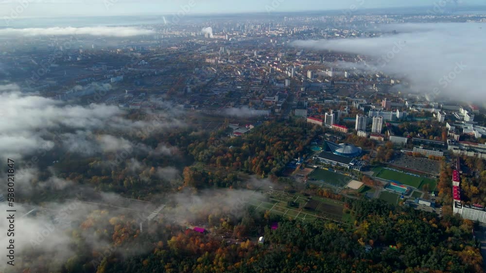Drone flight over the autumn city through the fog on a sunny morning.
Drone flight over the autumn city through the fog on a sunny morning.