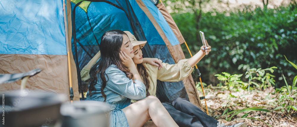 Asian pretty woman and friend use smartphone selfie on camping
