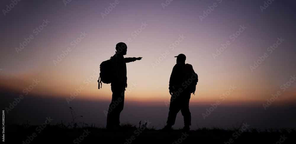 Silhouette of Hiker men with backpack stay on cliff and think on the top mountain at sunset