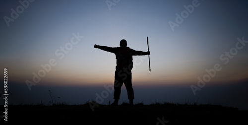 Silhouette of cheering hiking man open arms to the sunrise stand on mountain