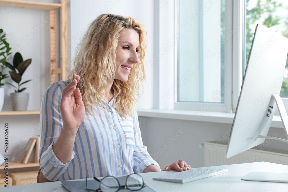 Beautiful young woman using video chat at desk in office Beautiful young woman using video chat at desk in office