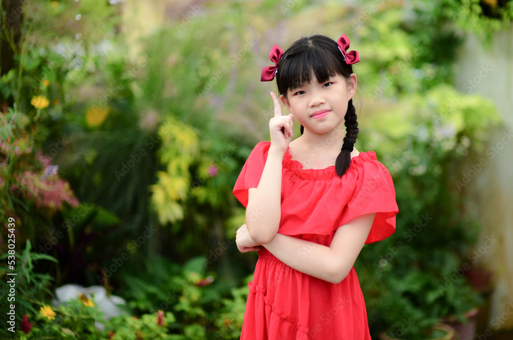 Young pretty girl holding finger up having idea and posing in nice garden Young pretty girl holding finger up having idea and posing in nice garden