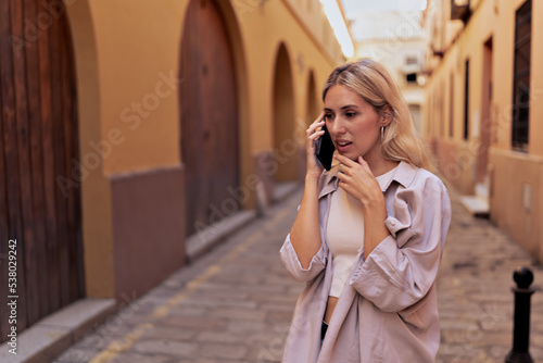 Young woman talking on cell phone in the street, concept of telephone assistance. Horizontal image with copy space. photo