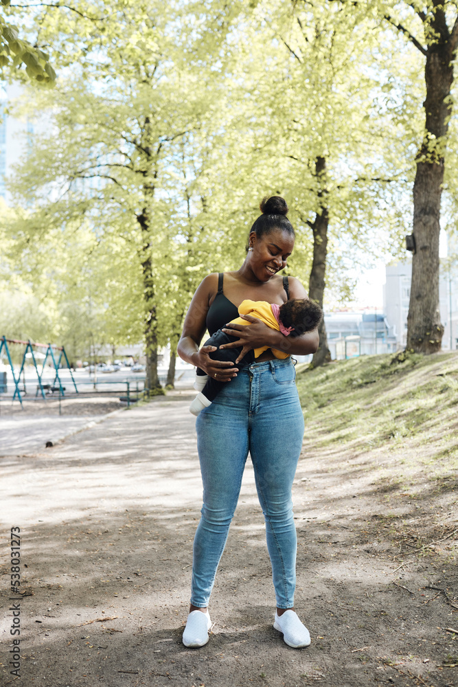 Smiling mother looking at daughter breastfeeding at park Smiling mother looking at daughter breastfeeding at park