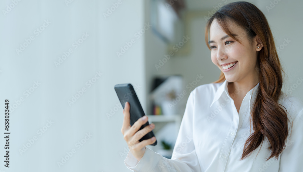 Happy young asian business woman wearing suit holding mobile phone Happy young asian business woman wearing suit holding mobile phone