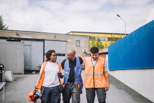 Female construction worker talking with male colleagues while walking on road photo