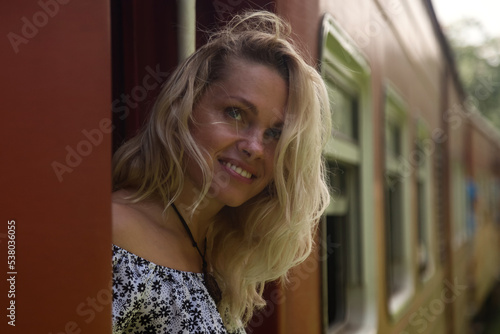 Smiling woman tourist travel by train and exploration to landmarks in Sri Lanka. Romantic traveler lady enjoying extreme fun train ride in tropical country. Journey of world concept. Copy space