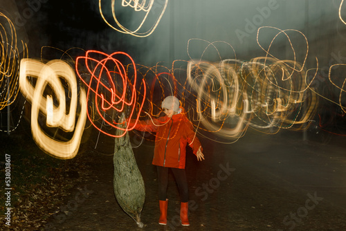Girl with red jacket playin with a christmas tree in the street with lights
