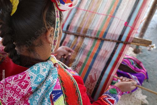 Cusco, Peru - 1 July, 2022: A Quechua lady weaves traditional Andean textiles using alpaca wool photo
