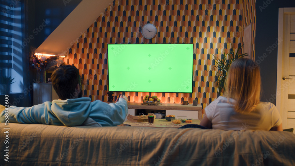 © Framestock - Woman switching channels with remote control. Couple sitting on couch in living room, talking, watching breaking news, movie or series on TV. Resting at home in the evening. Green screen. Chromakey. © Framestock - Woman switching channels with remote control. Couple sitting on couch in living room, talking, watching breaking news, movie or series on TV. Resting at home in the evening. Green screen. Chromakey.