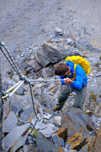 Alpinista supera le corde fisse verso la vetta del Pizzo Scopì, Alpi Lepontine, gruppo dell'Adula, Svizzera