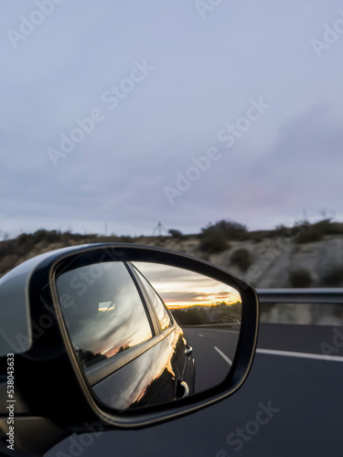 sunset through the rearview mirror of a car