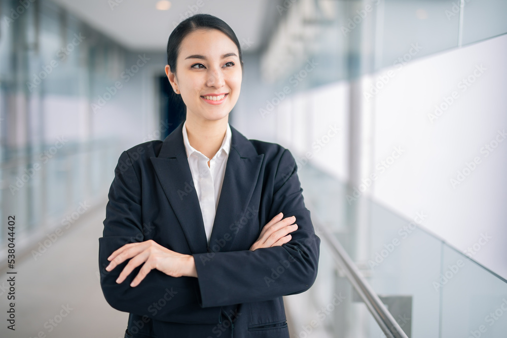 Happy young asian businesswoman smiling while walking against street blurred building background. Happy young asian businesswoman smiling while walking against street blurred building background.