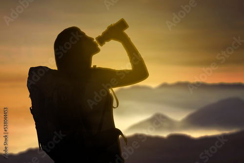 Silhouette of female hiker drinking after hikes