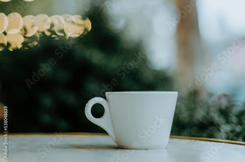 Coffee cup on outdoor terrace table with bokeh Christmas lights background