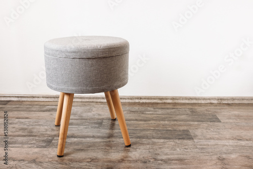 Trendy stool with build-in storage. Side view, white wall, space for