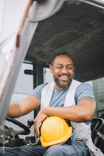 Happy construction worker with hardhat sitting in vehicle photo
