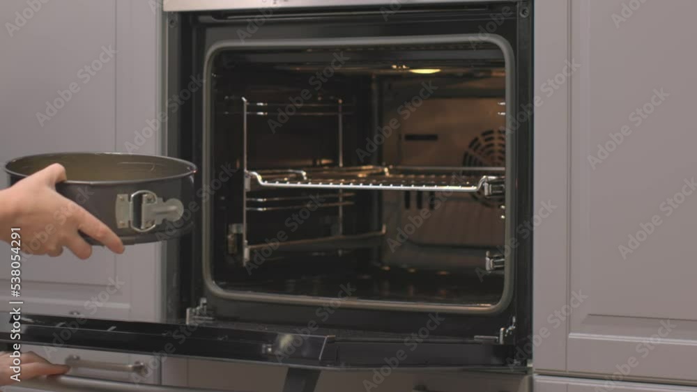 female hands open oven put cake to bake in hot stove cooking pumpkin pie thanksgiving traditional cake step by step recipe. Gray kitchen furniture steel black oven inside green shirt Caucasian woman female hands open oven put cake to bake in hot stove cooking pumpkin pie thanksgiving traditional cake step by step recipe. Gray kitchen furniture steel black oven inside green shirt Caucasian woman