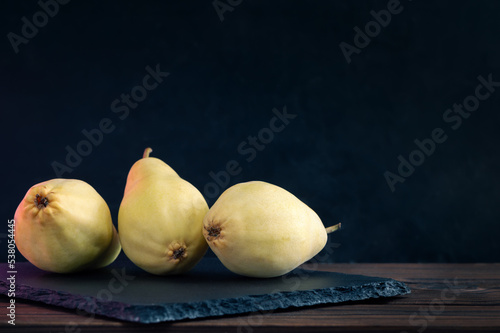Three Whole Pears Lie On A Slate Board. Healthy Food. Eco-Friendly Products. Selective Focus. Side View. Dark Background.