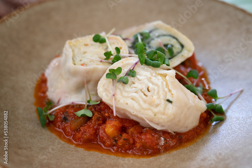 Three pieces of "struklji", Slovenian cheese dumplings, a traditional Slovene dish, composed of dough and various types of filling, served with vegetables sauce 