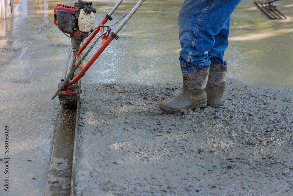 It is necessary to use machine to align fresh concrete compacted layer on new driveway construction It is necessary to use machine to align fresh concrete compacted layer on new driveway construction
