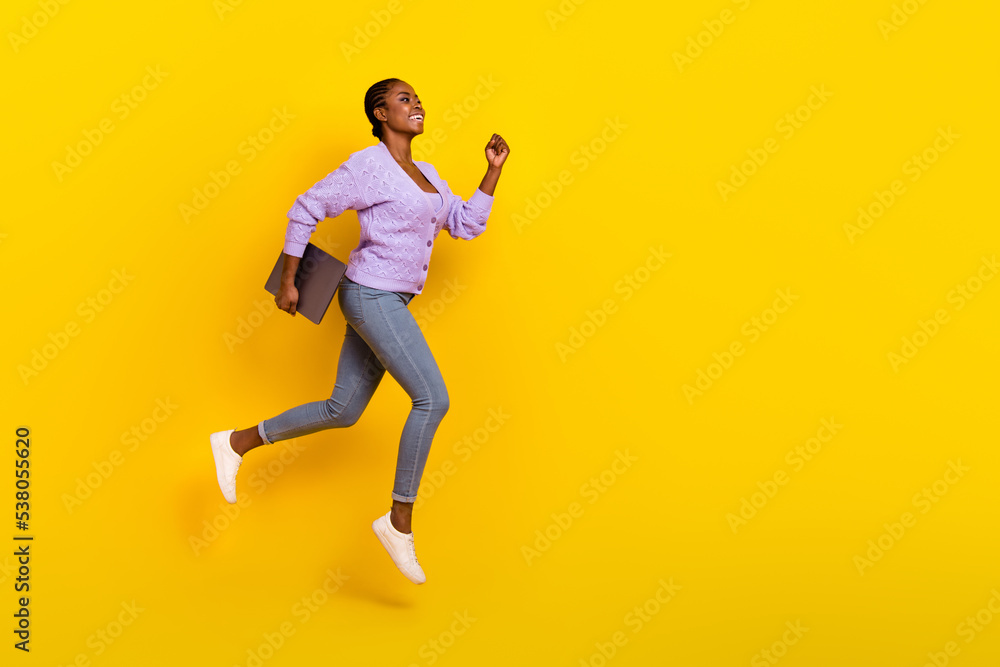Full size profile portrait of excited active lady run jump look empty space hold netbook isolated on yellow color background