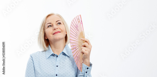 Beautiful middle aged woman with menopause blowing by fan. Hormone replacement therapy and mature woman healthcare. Mid age happy women lifestyle. Senior woman isolated on grey. photo