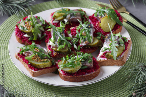 Danish smorrebrods with salted herring, beetroot, pickled cucumber and mustard