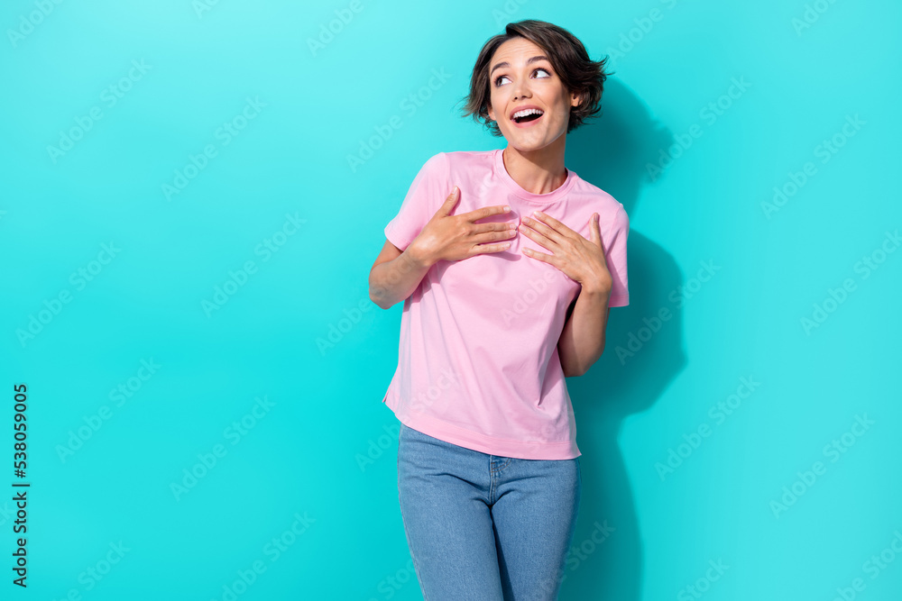 Portrait photo of young attractive cute funny lady touch hands chest looking empty space surprised lovely isolated on cyan color background Portrait photo of young attractive cute funny lady touch hands chest looking empty space surprised lovely isolated on cyan color background