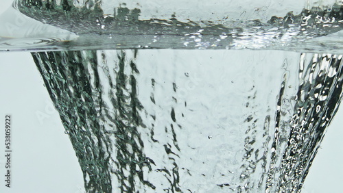 Green avocado splashing water surface closeup. Organic tropical ingredient fall