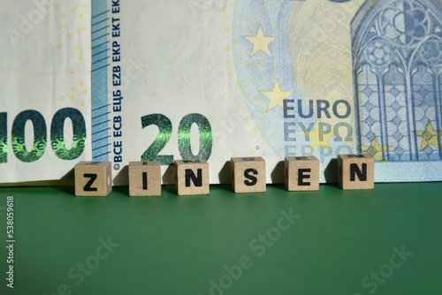 Das Wort Zinsen mit Holzbuchstaben auf Euroscheinen