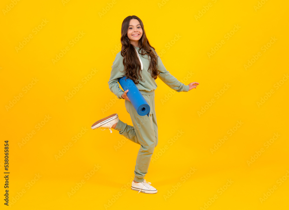 Teen girl 12, 13, 14 years old in sport suit. Fashion child in sportswear sportive clothing. Sportive fashionable outfit. Studio shot on yellow background.