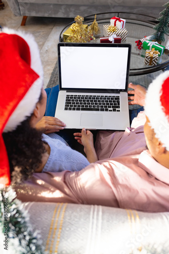 African american couple wearing santa claus hats, using laptop with copy space