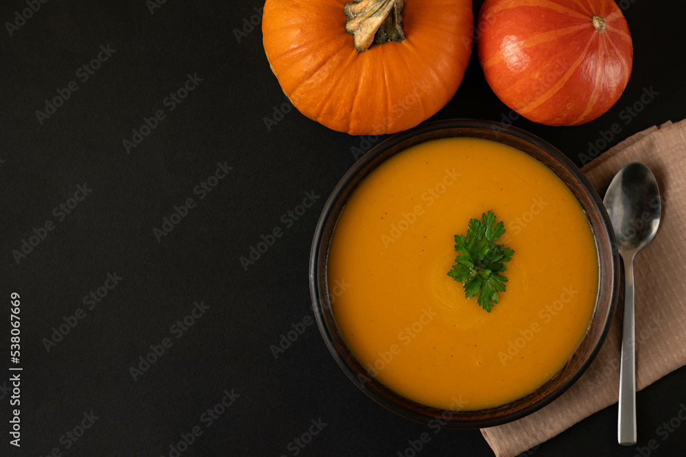 Pumpkin soup in a bowl on a dark background. Pumpkin soup in a bowl on a dark background.