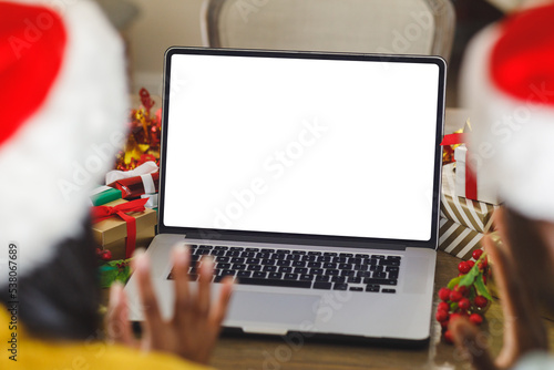 Diverse couple in santa hats making christmas video call on tablet with copy space on screen